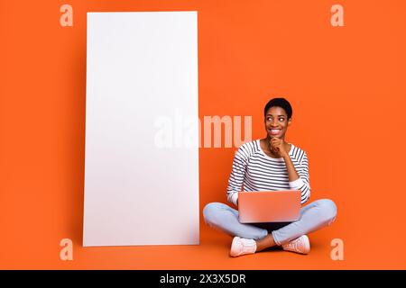 Foto von nachdenklichen dritten Geschlecht Person tragen Pullover chatten moderne Gerät leeren Raum isoliert orange Farbe Hintergrund Stockfoto