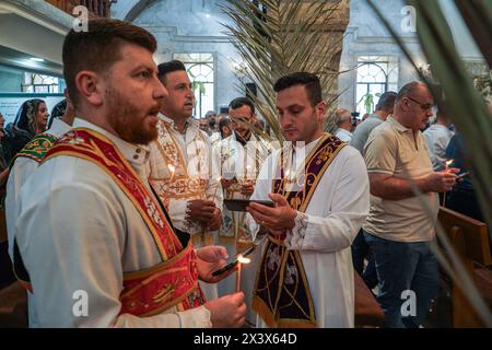 Bartella, Irak. April 2024. Die Diakone halten während des Palmensonntaggottesdienstes Kerzen, der den Beginn der Karwoche für orthodoxe Christen in der syrisch-orthodoxen Kirche Mart Shmoni markiert. Quelle: SOPA Images Limited/Alamy Live News Stockfoto