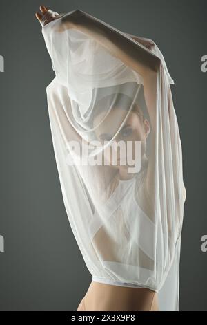 Eine junge, schöne Ballerina in einem transparenten weißen Kleid mit Schleier, anmutig tanzend. Stockfoto