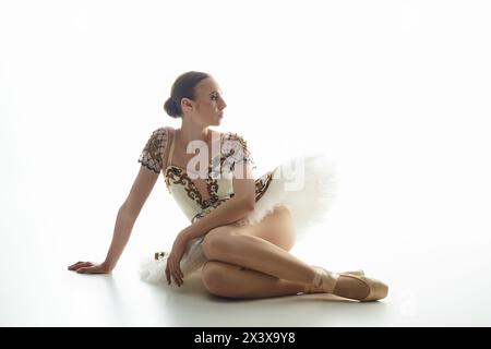 Eine Frau sitzt anmutig auf dem Boden, die Beine überkreuzt. Stockfoto