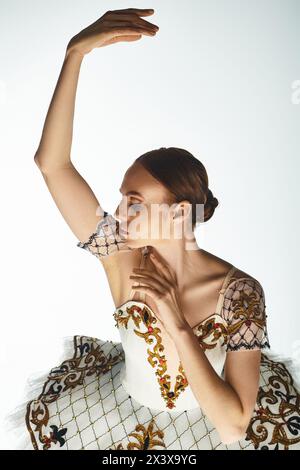 Junge, schöne Ballerina in weiß-goldenem Kleid, die anmutig tanzt. Stockfoto