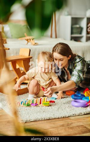 Eine junge Mutter engagiert sich freudig mit ihrer Tochter auf dem Boden und fördert durch Spiel und Interaktion eine starke Bindung. Stockfoto