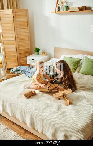 Eine junge Mutter liest ihrem Kleinkind auf einem gemütlichen Bett ein Buch vor und schafft so einen besonderen Moment voller Staunen und Fantasie. Stockfoto