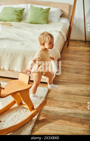 Ein junges Kleinkind spielt freudig auf einem Holzschaukelspielzeug in gemütlicher Atmosphäre. Stockfoto