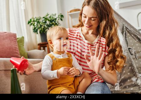 Eine junge Mutter und ihre Tochter spielen zu Hause fröhlich zusammen auf dem Boden und schaffen bleibende Erinnerungen. Stockfoto