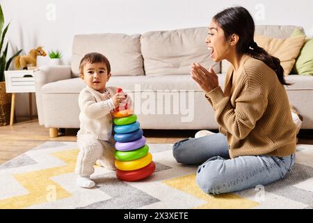 Eine junge asiatische Mutter setzt sich freudig mit ihrem kleinen Sohn auf dem Boden ihres gemütlichen Wohnzimmers in Verbindung. Stockfoto