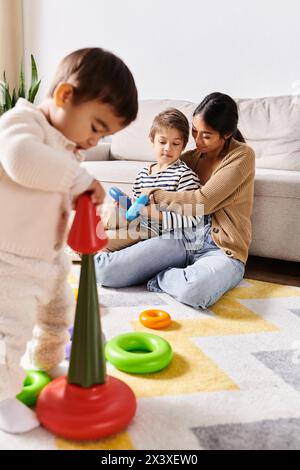 Die junge asiatische Mutter spielt mit ihren beiden kleinen Söhnen im gemütlichen Wohnzimmer mit Spielzeug und erforscht sie. Stockfoto