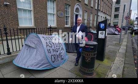 Menschen, die an Zelten vorbeilaufen, in denen Asylbewerber untergebracht sind, in der Nähe des Verbindungsbüros des Europäischen Parlaments in Dublin. Behauptungen, dass die Mehrheit der Asylbewerber aus Nordirland die Grenze überschritten habe, wurden von Menschenrechts- und Flüchtlingsorganisationen in Frage gestellt. Irlands Justizministerin Helen McEntee behauptete letzte Woche, dass die Zahl der Asylbewerber, die von Nordirland in den Staat überquerten, jetzt "über 80 %" sei, nachdem sich die Migrationsmuster in den letzten Monaten verändert hatten. Bilddatum: Montag, 29. April 2024. Stockfoto