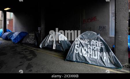 Menschen, die an Zelten vorbeilaufen, in denen Asylbewerber untergebracht sind, in der Nähe des Internationalen Schutzamtes in Dublin. Behauptungen, dass die Mehrheit der Asylbewerber aus Nordirland die Grenze überschritten habe, wurden von Menschenrechts- und Flüchtlingsorganisationen in Frage gestellt. Irlands Justizministerin Helen McEntee behauptete letzte Woche, dass die Zahl der Asylbewerber, die von Nordirland in den Staat überquerten, jetzt "über 80 %" sei, nachdem sich die Migrationsmuster in den letzten Monaten verändert hatten. Bilddatum: Montag, 29. April 2024. Stockfoto