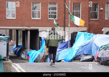 Menschen, die an Zelten vorbeilaufen, in denen Asylbewerber untergebracht sind, in der Nähe des Internationalen Schutzamtes in Dublin. Behauptungen, dass die Mehrheit der Asylbewerber aus Nordirland die Grenze überschritten habe, wurden von Menschenrechts- und Flüchtlingsorganisationen in Frage gestellt. Irlands Justizministerin Helen McEntee behauptete letzte Woche, dass die Zahl der Asylbewerber, die von Nordirland in den Staat überquerten, jetzt "über 80 %" sei, nachdem sich die Migrationsmuster in den letzten Monaten verändert hatten. Bilddatum: Montag, 29. April 2024. Stockfoto