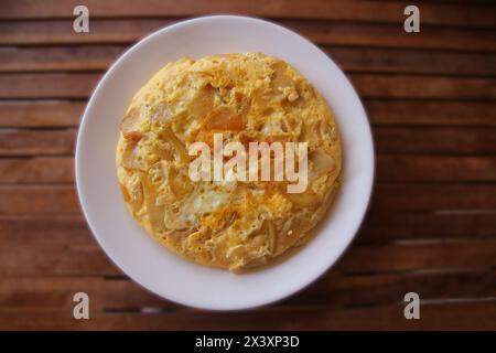 Weißer Teller mit hausgemachter Tortilla espanola - ein traditionelles spanisches Gericht auf Holztisch in Bokeh Stockfoto