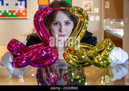 London, Großbritannien. 29. April 2024. Ein Mitarbeiter mit zwei Werken aus dem sechs „Ballon Animals Collector's Set“, 2017-2019, von Jeff Koons, (Est. £50.000 - £70.000), bei der Vorschau von „Hot Off the Press“, einem Verkauf von Drucken und Neuauflagen, die in den letzten fünfzig Jahren von bekannten zeitgenössischen Künstlern erstellt und veröffentlicht wurden. Die Arbeiten werden am 1. Mai in der Bonhams New Bond Street versteigert. Quelle: Stephen Chung / Alamy Live News Stockfoto