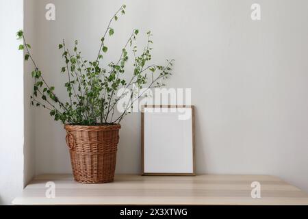Frühling, Osterstillleben. Elegantes skandinavisches Wohnzimmer, Home Office. Leeres vertikales Holzbild-Modell auf Schreibtisch, Tisch. Weidenweide Stockfoto