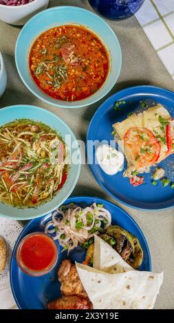 Auswahl an Speisen auf rustikalem Tisch mit Sushi, Salat, Suppe, Fleisch. Wunderschön präsentiert und lecker. Stockfoto