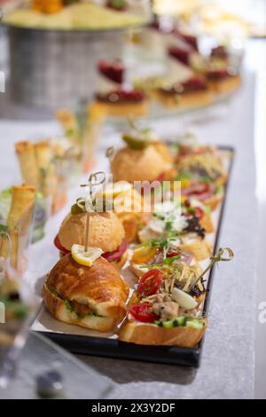 Eine köstliche Auswahl an frisch gebackenen Croissants und Gourmet-Sandwiches auf einer Platte für eine Veranstaltung mit Catering. Stockfoto