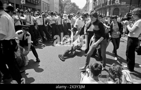 London, Großbritannien. Juni 1984. Polizeizusammenstoß mit gewaltlosen Aktivisten, die direkt auf der Straße zum Grosvenor Square, London, am 9. Juni 1984 blockieren. Die Aktion war eine Reaktion auf den Besuch des amerikanischen Präsidenten, Ronald Reagans auf dem Weltwirtschaftsgipfel in London und die Stationierung von US-amerikanischen Kreuzfahrtraketen in Großbritannien. Der Protest fiel zeitgleich mit der Anti-Cruise-Raketen-Kundgebung des CND auf dem Trafalgar Square, London, zusammen. Der Grosvenor Square war zum Zeitpunkt des Protestes der Sitz der amerikanischen Botschaft in Großbritannien. Stockfoto