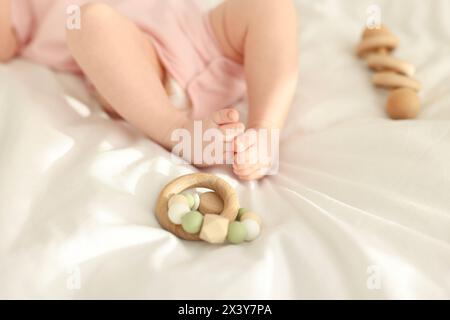 Niedliches Baby und Rasselspielzeug auf Laken, Nahaufnahme Stockfoto