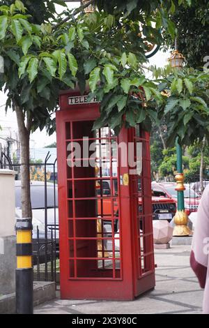 Die rote Telefonbox auf der Straßenseite ist eine Dekoration auf dem Bürgersteig in der Touristengegend Stockfoto