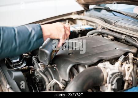 Ein Mann gießt Motoröl in einen Automotor. Öl wechseln und nachfüllen, Fahrzeugwartung. Stockfoto