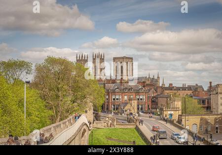 Von den historischen Stadtmauern aus hat man einen Blick auf die Türme des York Minster, die sich über den Dächern der Stadt erheben. Touristen laufen an der Mauer und Leute und Tram Stockfoto