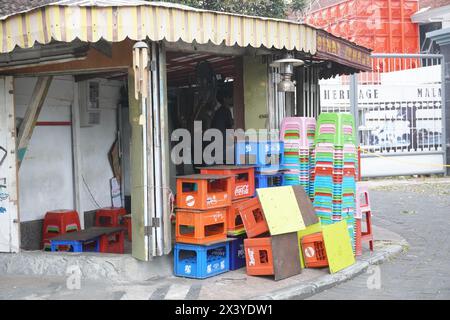 Stapel leerer Getränkeflaschenkisten und Stapel kurzer Plastikstühle in einem alten Laden am Straßenrand Stockfoto