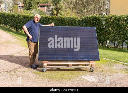 Senior Mann mit Photovoltaik-Solarmodul im Garten. Stockfoto