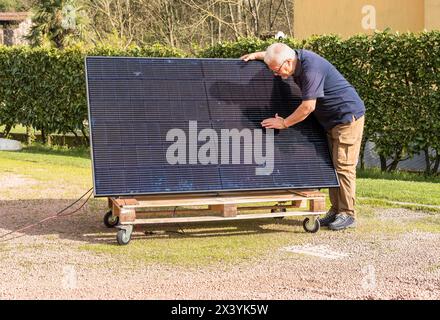 Senior Mann mit Photovoltaik-Solarmodul im Garten. Stockfoto