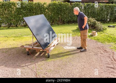 Senior Mann mit Photovoltaik-Solarmodul im Garten. Stockfoto