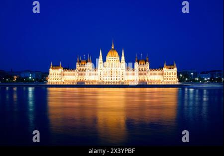 Parlament in Budapest bei Nacht, beleuchtetes historisches Gebäude, das sich im Wasser des Flusses spiegelt Stockfoto