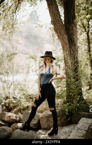 Schicke Pose am Fluss; blond in blauem Body und schwarzer Kleidung Stockfoto