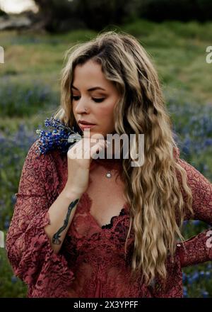 Ätherischer Moment, blond in Rosa zwischen Lupinen in der Abenddämmerung Stockfoto