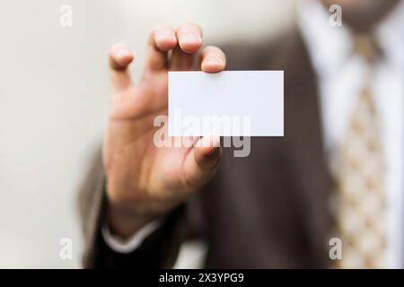 Geschäftsmann hält eine weiße Karte in der Hand. Sie können einen Text, eine Nachricht oder ein Logo auf die leere Oberfläche setzen. Stockfoto
