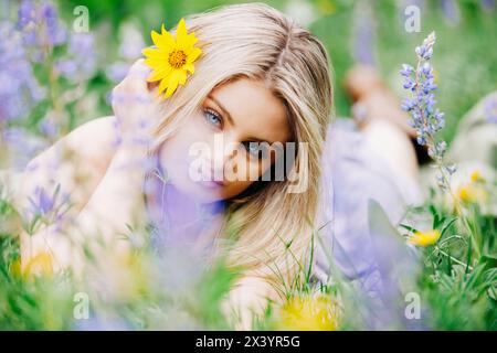 Nahaufnahme eines Teenager-Mädchens, das auf dem Boden liegt, umgeben von Wildblumen Stockfoto