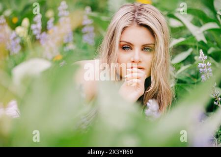 Nahaufnahme eines Teenager-Mädchens, das inmitten von Wildblumen im Wald liegt Stockfoto