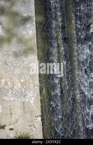 Eine Betonrampe, um Wasser aus einem Damm voller Unkraut und Algen zu evakuieren Stockfoto