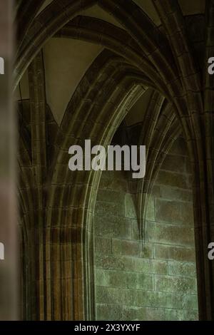 Blick auf die gotischen Rippengewölbe und die Säulen. Vertikale Aufnahme der gewölbten gotischen Bögen in einer Kathedrale. Stockfoto