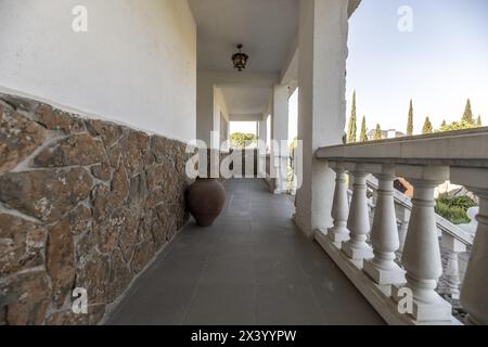 Weiße Balustraden einer langen Terrasse Außenterrasse eines Einfamilienhauses mit einem Tontopf mit dekorativen Funktionen auf einem grauen Terrazzo-Boden Stockfoto