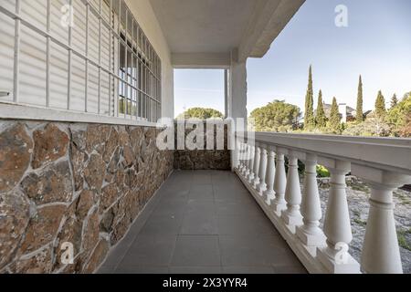 Weiße Balustraden einer langen Terrasse, Außenterrasse eines Einfamilienhauses mit Metallstangen an den Fenstern Stockfoto