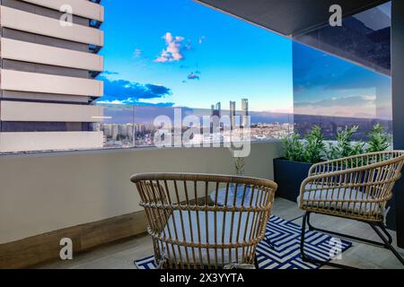 Eine Außenterrasse eines Hauses mit Korbsesseln und Blick auf die Skyline von Madrid Stockfoto