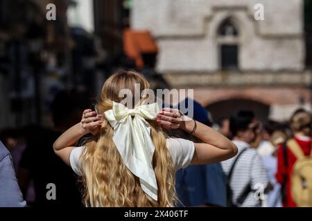 Krakau, Polen. April 2024. Eine junge Frau, die leicht gekleidet ist, wird auf einem Hauptmarkt in der Altstadt von Krakau gesehen, als eine Hitzewelle in Polen eintrifft, die fast 30 Grad Celsius erreicht - eine sehr ungewöhnliche Temperatur für April. Quelle: SOPA Images Limited/Alamy Live News Stockfoto