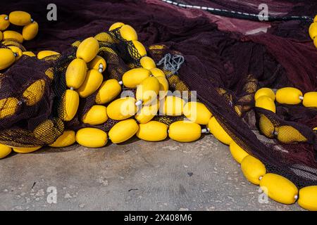 Gelbe Fangbojen, die in dunklen Netzen verstreut sind und die rohen Werkzeuge des Fischhandels fangen. Hochwertige Fotos Stockfoto