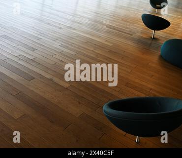 Inmitten der ruhigen Leere des Raumes steht eine Sammlung von Holzstühlen anmutig auf dem glatten, polierten Holzfußboden und strahlt einen Hauch von e aus Stockfoto