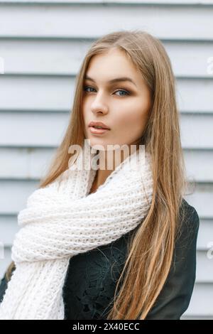 Junges hübsches Mädchen mit Einem weißen Strickschal am Herbsttag auf der Holzwand im Hintergrund Stockfoto