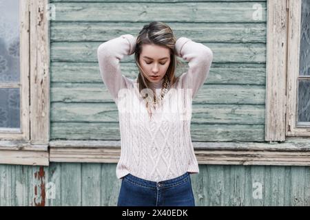 Porträt Eines jungen schönen Mädchens mit dem rosafarbenen Pullover auf grünem Hintergrund der alten Holzwand. Er Schaut Nach Unten Stockfoto