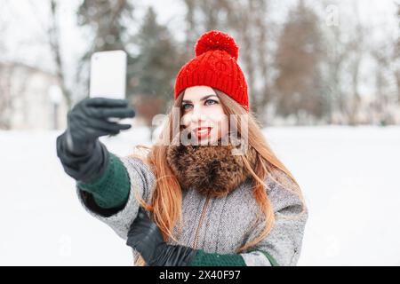 Niedliches Mädchen fotografierte sich am Telefon auf dem Hintergrund Einer Winterstadt Stockfoto