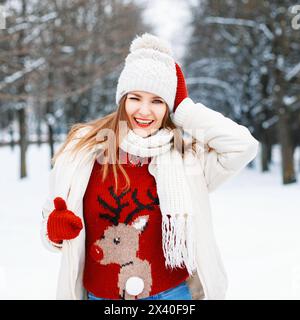 Ein glückliches junges Mädchen in Einem roten Pullover mit Einem Hirsch winkt und lächelt Stockfoto