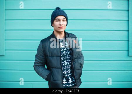 Junger gutaussehender Kerl in warmen Stricksachen vor Einem Hintergrund einer farbigen Holzwand Stockfoto