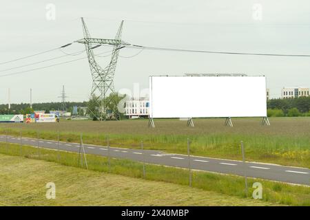 Eine große Plakatwand, die gut sichtbar am Straßenrand steht und vorbeifahrenden Fahrern und Fußgängern ein Mockup-Banner zeigt. Stockfoto