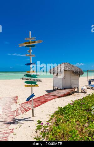 Wegweiser an einem tropischen weißen Sandstrand, der die Entfernung zu Ländern auf der ganzen Welt von Kuba in der Karibik zeigt; Cayo Guillermo, Kuba Stockfoto