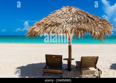 Sonnenliegen im Schatten am Strand Playa Pilar auf Cayo Guillermo im Jardines del Rey Archipel, mit klarem türkisfarbenem Wasser und Horizont im Jahr ... Stockfoto